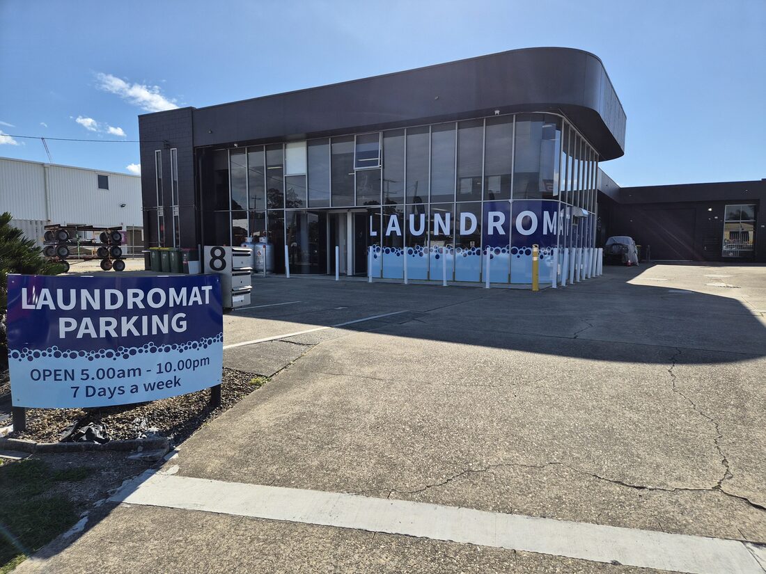 Keep It Clean Laundromat shopfront window showing logo and opening hours 5am-10pm, 7 days